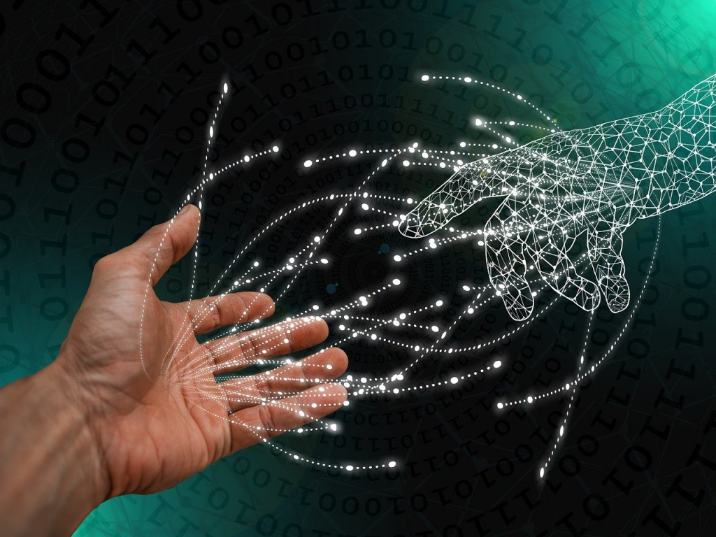 una mano humana entrelazándose con una mano robótica creada con nodos y líneas electrónicas conectados