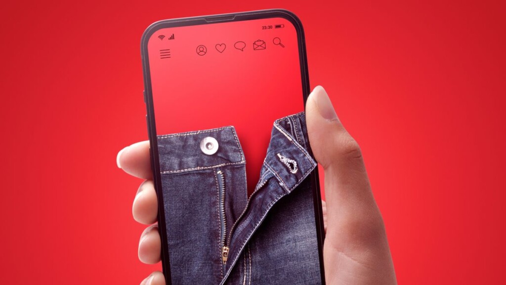 Una composición de un móvil, que muestra unos jeans desabrochados, sostenido en la mano de una chica.
